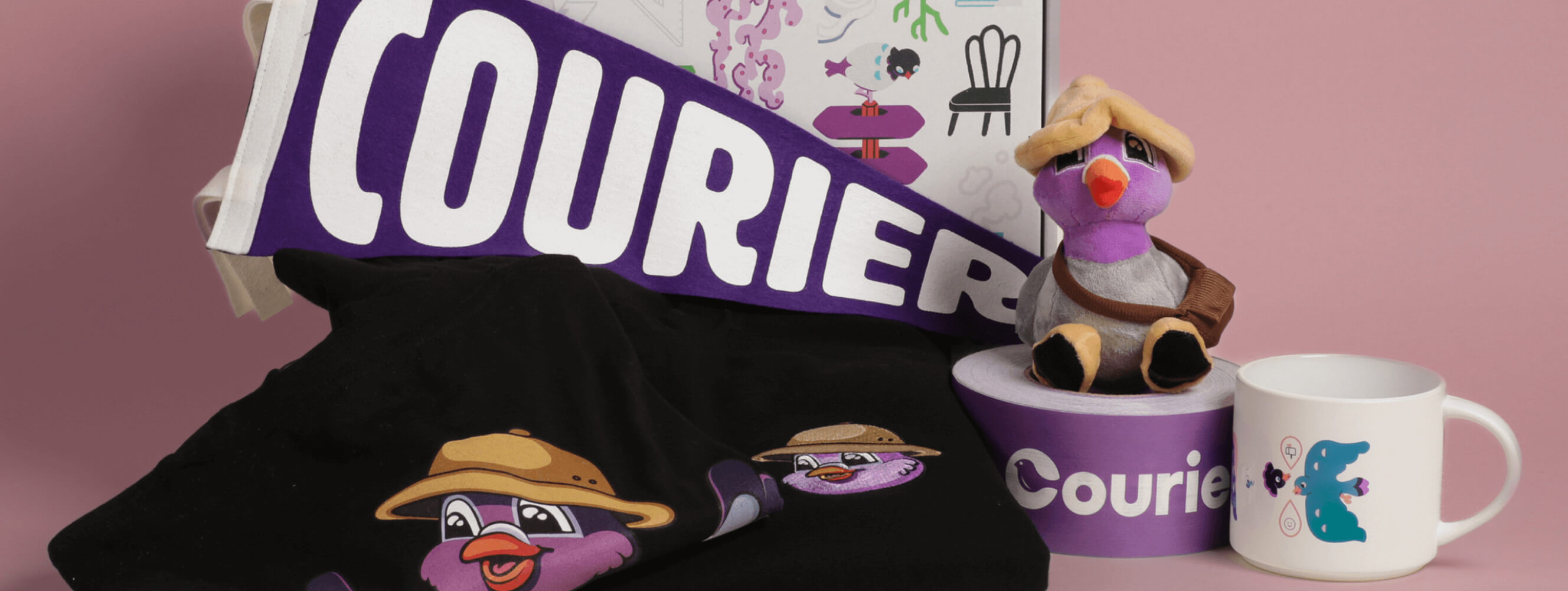 Photo of the welcome kit sent to Courier employees. The welcome kit box sits behind an assortment of swag, including a t-shirt with the company's mascot, Pip, and a plush of him, along with a mug, pennant, and packing tape with the Courier logo on it.