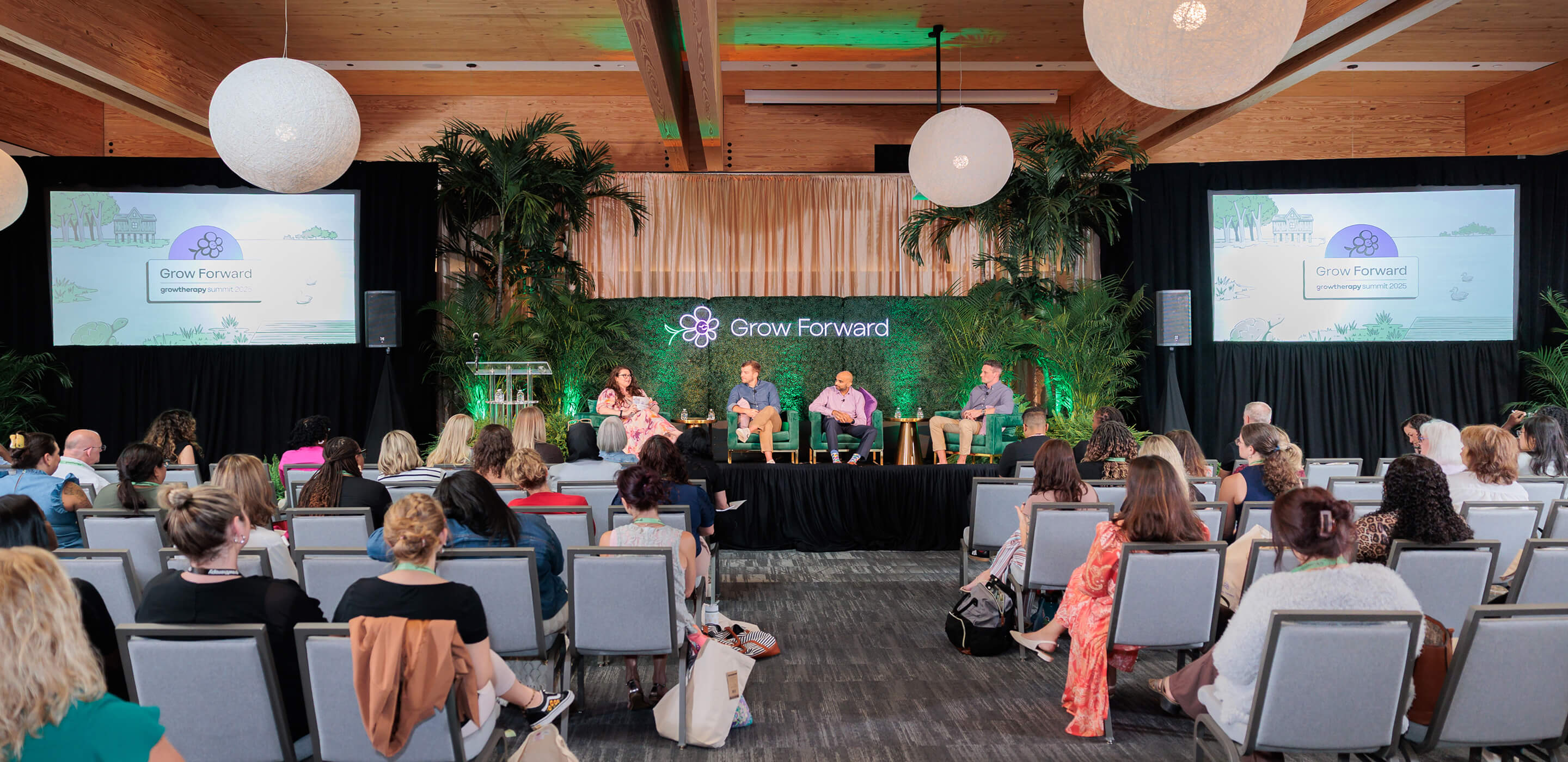 Photo of the stage at Grow Forward with a full audience and three guests sitting on the state, along with a host.