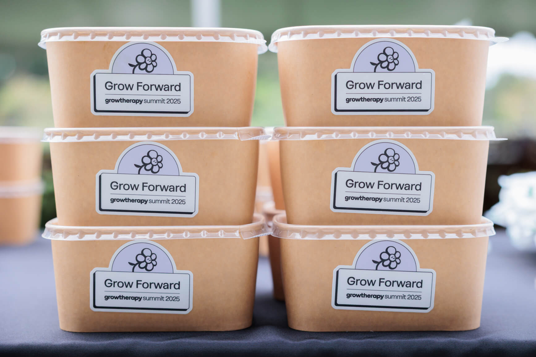 Two stacks of individual food containers with the Grow Forward logo on them.