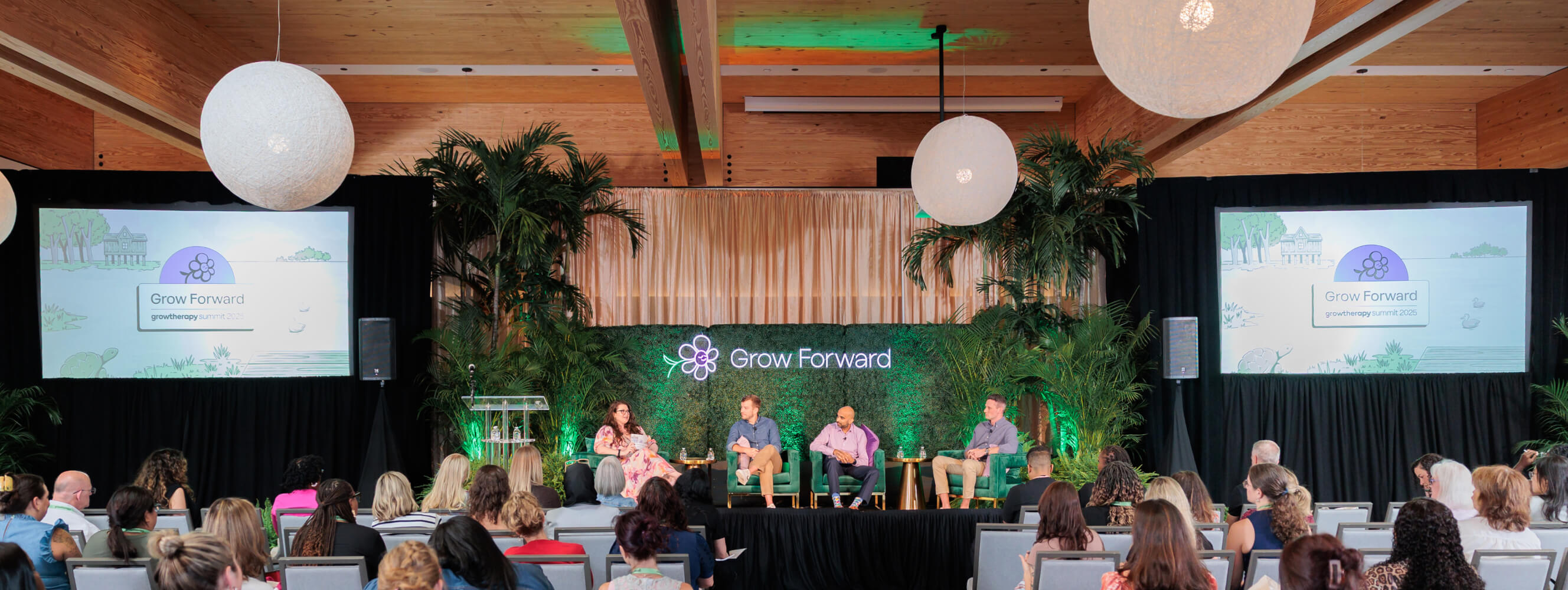 Photo of the stage at Grow Forward with a full audience and three guests sitting on the state, along with a host.