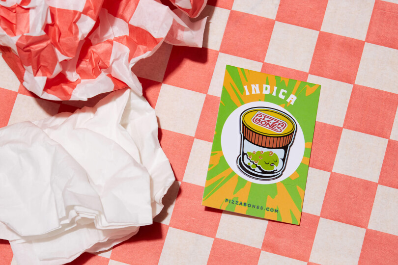 Photo of Indica pin. The background is checkered red and white, and there's a crumpled napkin nearby.